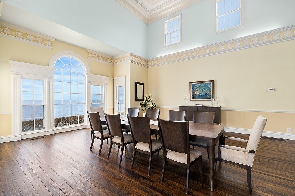 Double-height dining hall at 66 Ocean Street with a monumental arched Palladian window framing the open ocean, classical columns, and a long dining table
