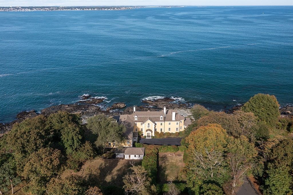 Aerial from the seaward side showing 66 Ocean Street set among trees at the edge of the rocky point with the wide open Atlantic stretching to the horizon